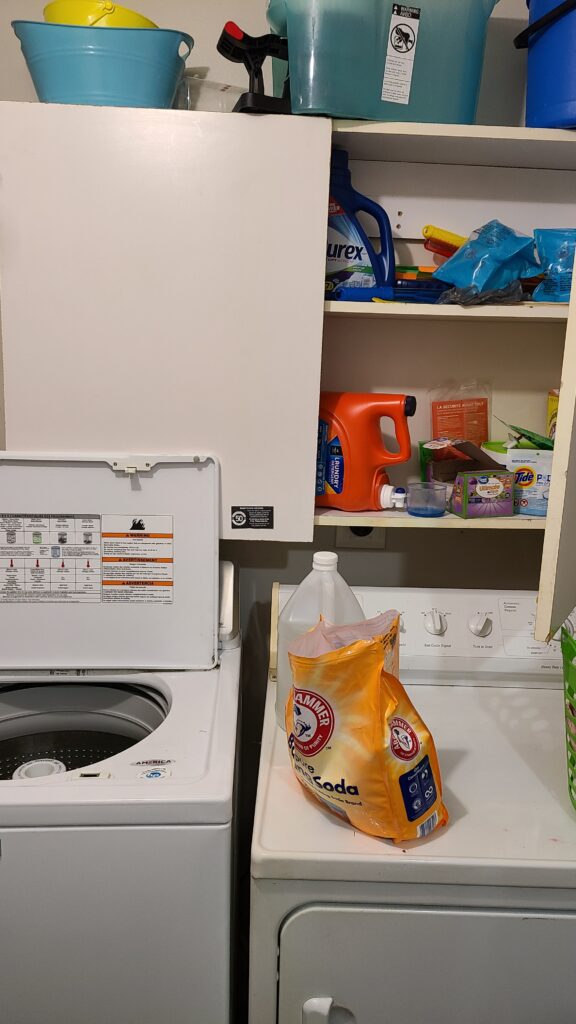 A closeup of the laundry room cabinet. One door is open, revealing cluttered items.