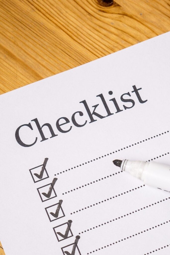 A white paper with the word "Checklist". Below are dotted lines with checkmarks next to them.
