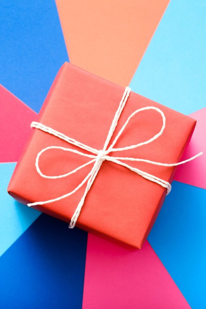 A square-shaped wrapped gift against a blue and pink background