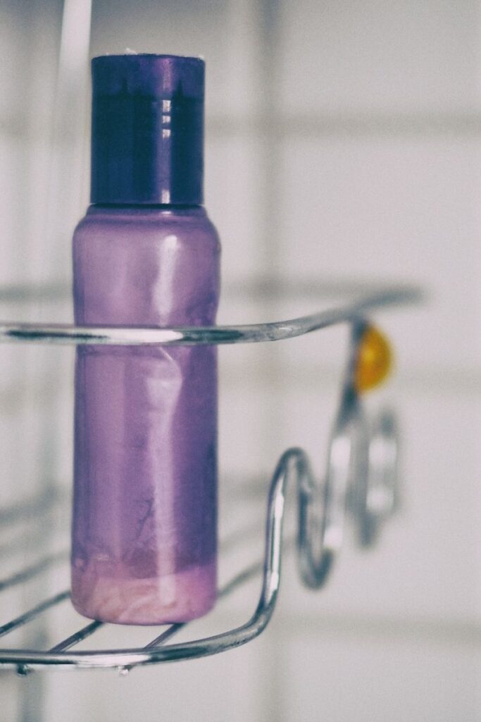 A closeup of a metal shower caddy. Sitting in it is a small soap bottle.