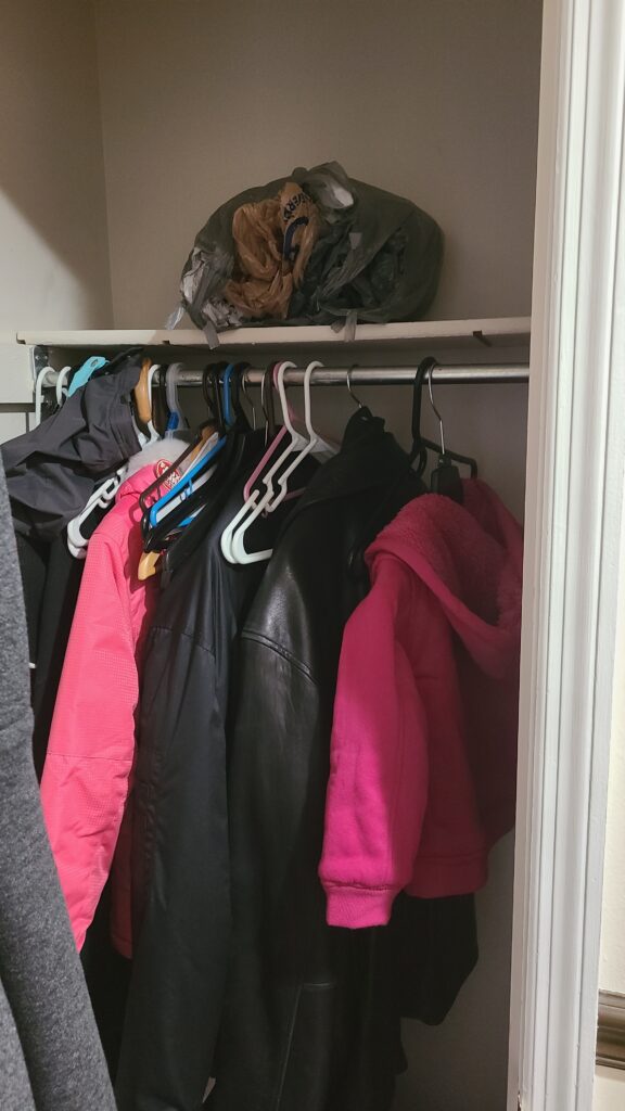 The top shelf of a closet. One bunch of plastic bags is sitting on top.