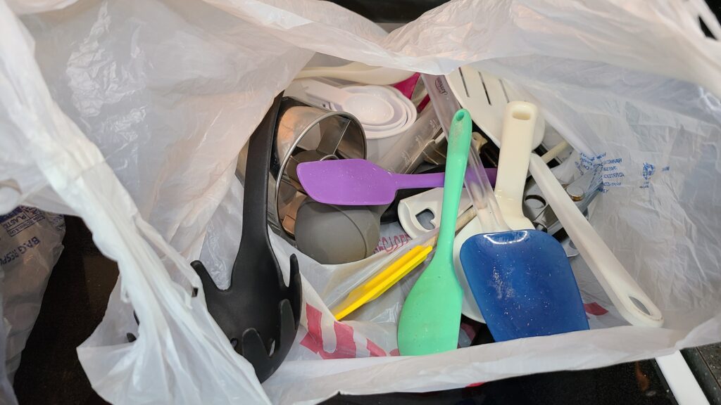 A plastic grocery bag filled with kitchen utensils