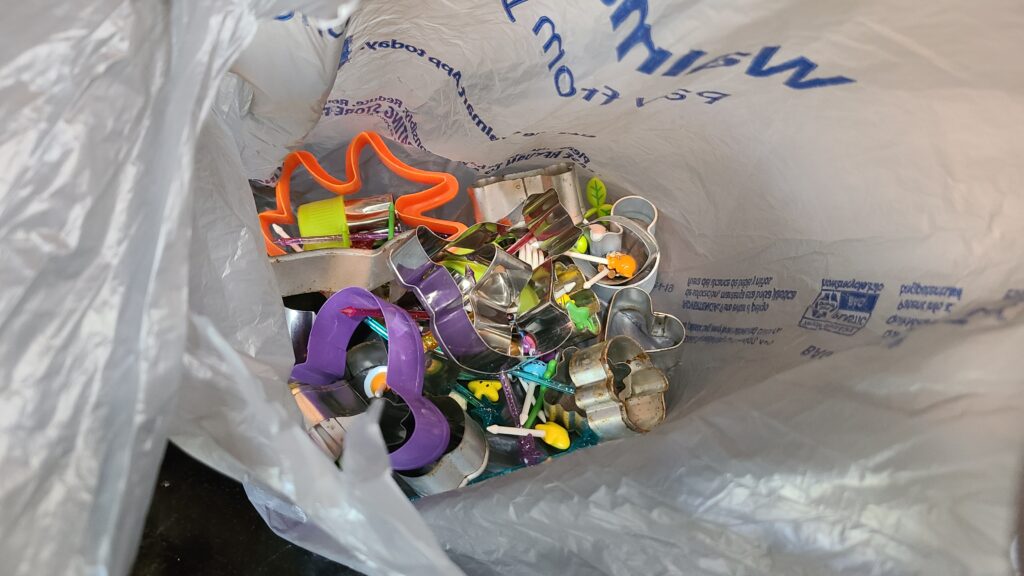 A plastic grocery bag filled with cookie cutters and food picks