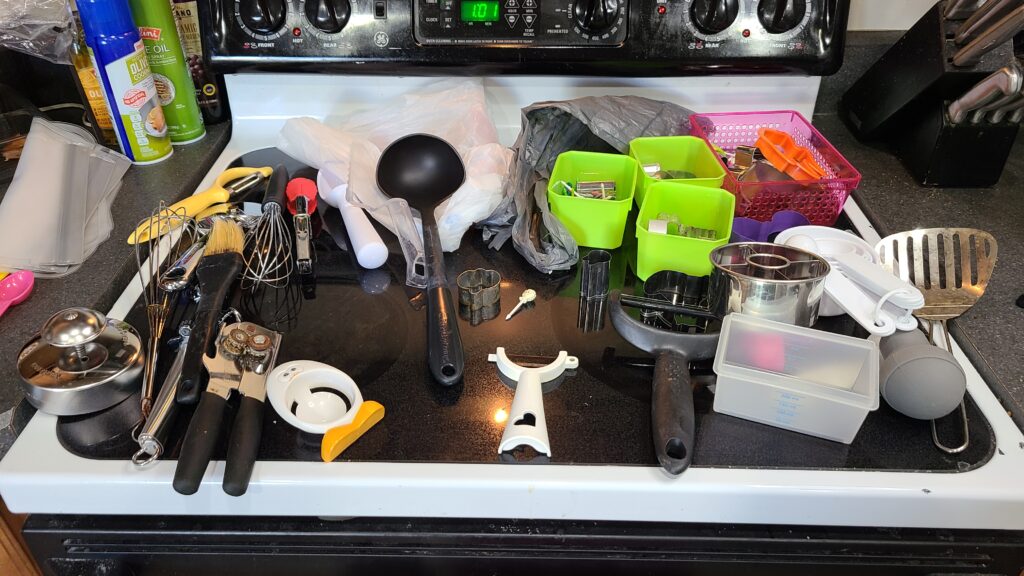 A stovetop covered with miscellaneous kitchen utensils