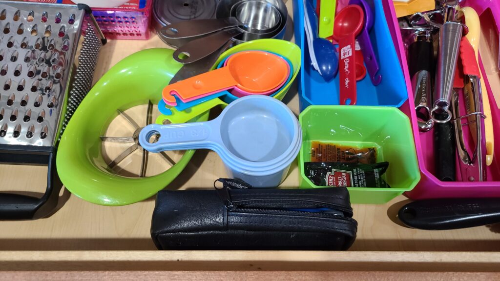 A closeup of the inside of a kitchen drawer. Inside are storage bins filled with organized utensils