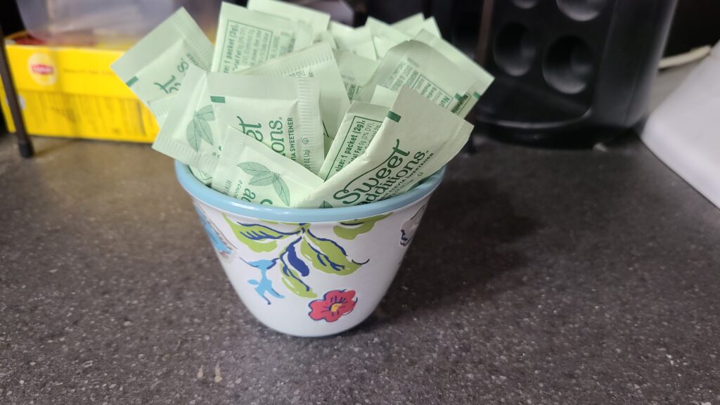 A small decorative bowl filled with sweetener packets