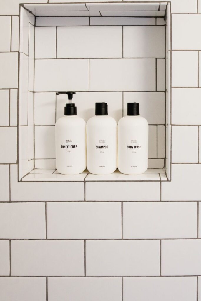 The wall of a shower with a built-in crevice. Inside is 3 shampoo bottles.