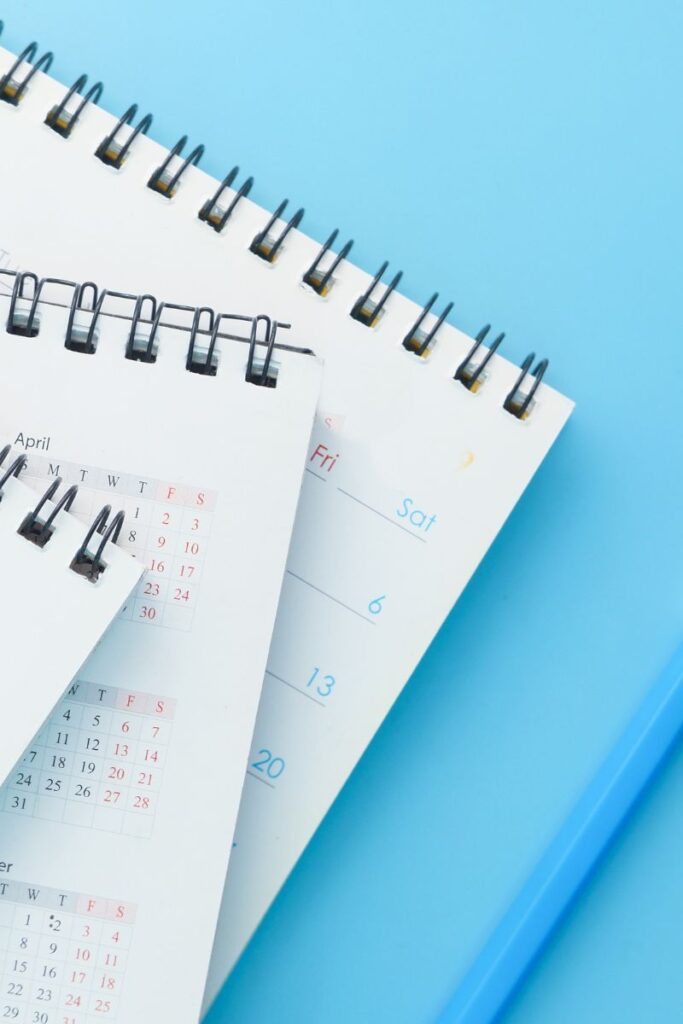 A pile of spiral bound calendars on a blue background
