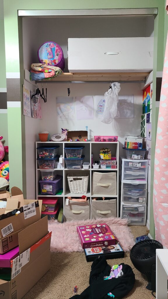 The inside of an open closet, containing a 9-cube shelf and stackable Sterilite drawers.