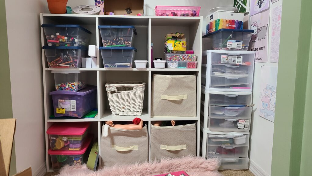 A closeup of the inside of an open closet. Inside is a 9-cube shelf and three stackable Sterilite drawers.