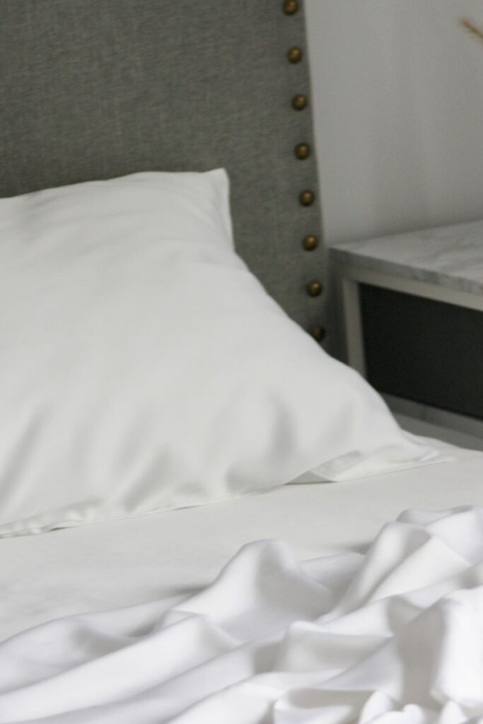A closeup of one side of a bed. The pillow and sheets are ruffled.