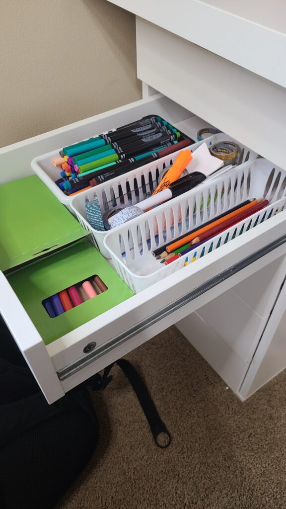 The inside of a desk drawer. Inside are small baskets of stationary.