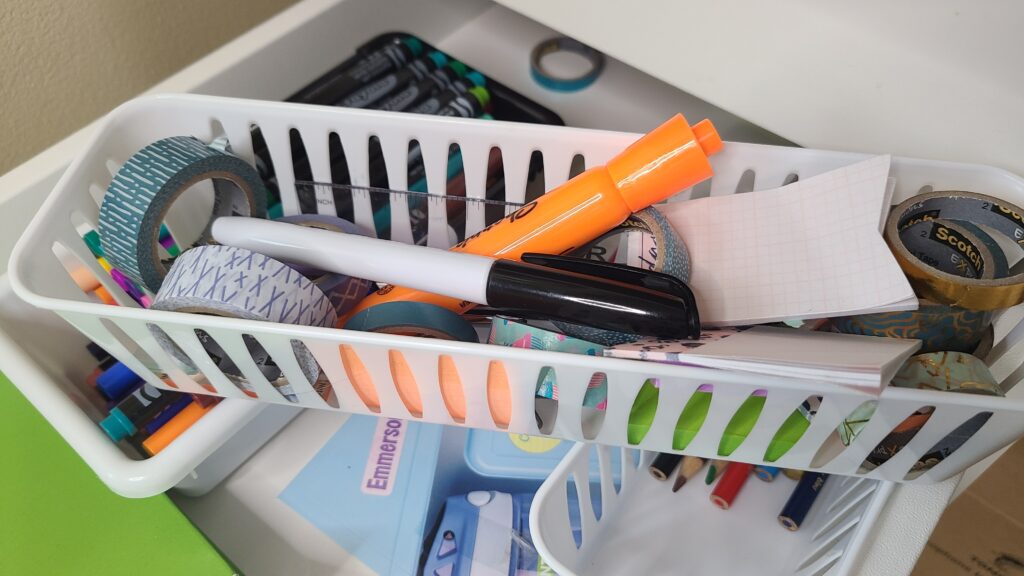 A small basket filled with washi tape, permanent marker, and sticky notes