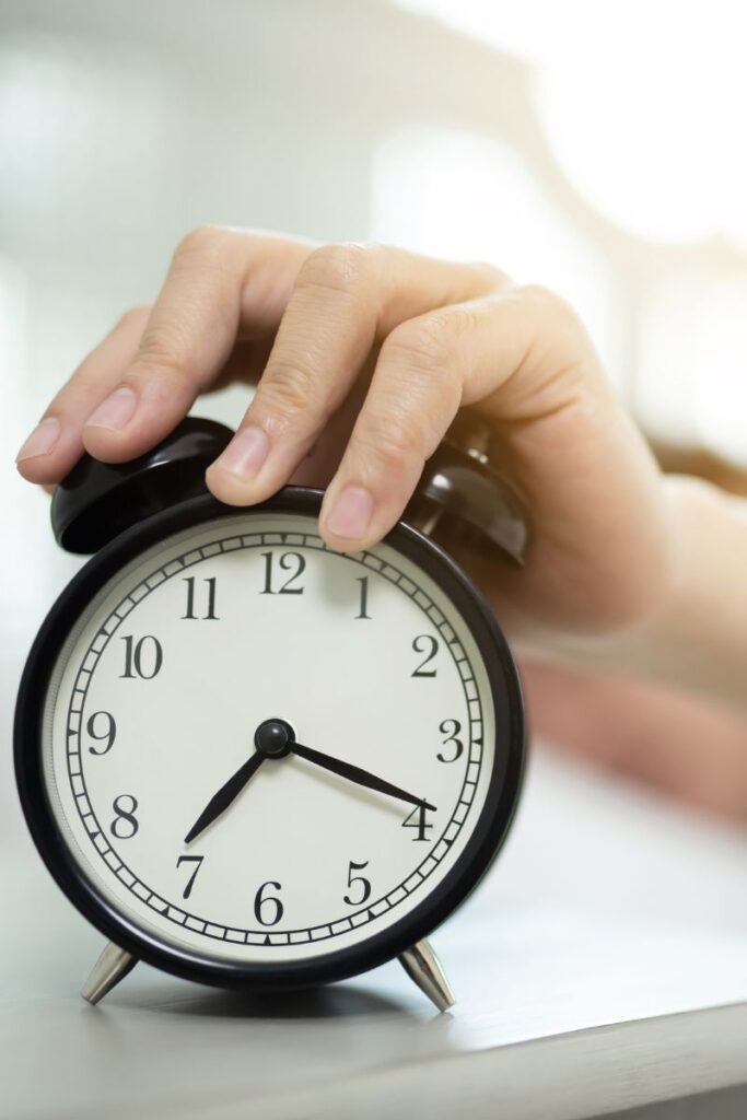 A hand turning off an alarm clock