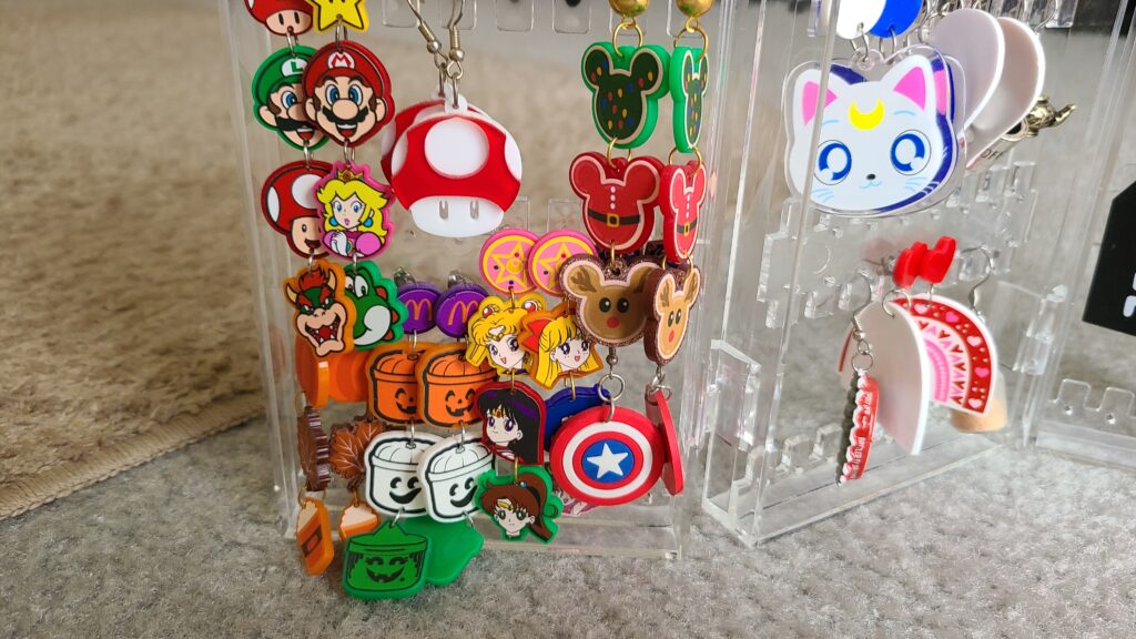 A close-up of an accordion-style earring holder, filled with Disney and video game-related earrings
