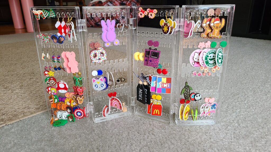 An accordion-style earring holder sitting on the floor, filled with earrings