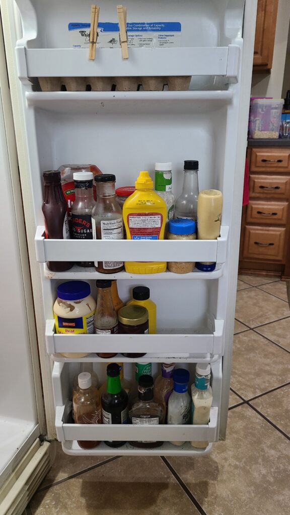 The inside of a fridge door, holding miscellaneous condiments