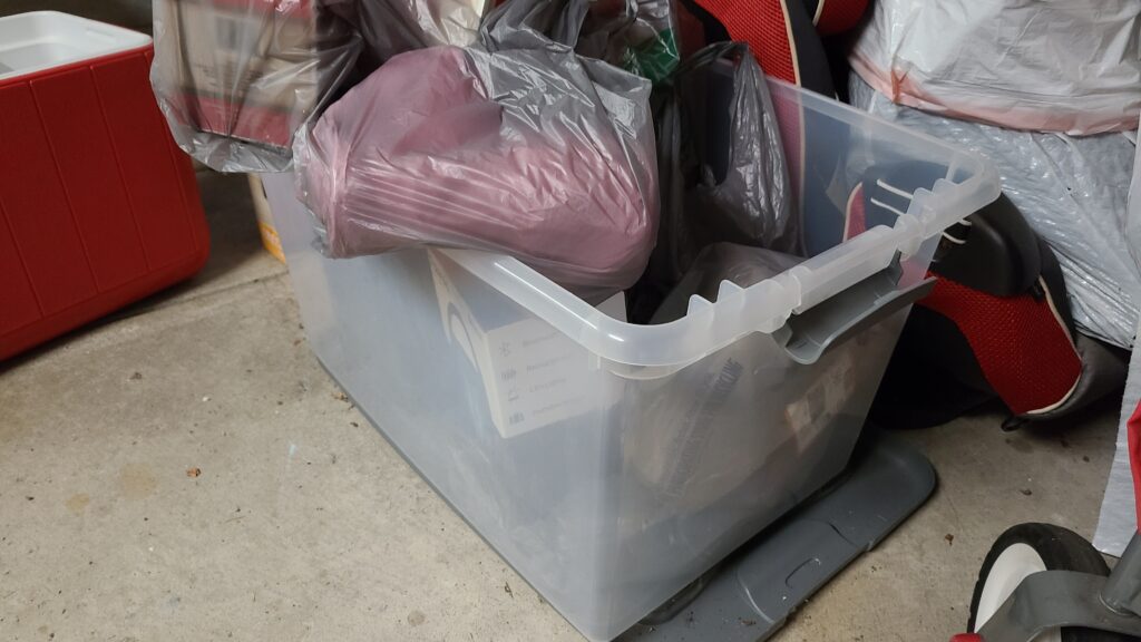 A large clear storage bin filled with donation items