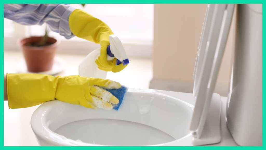 A person wearing gloves, scrubbing a toilet